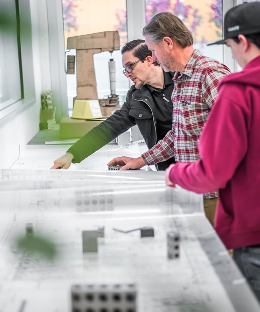 Three people looking at blueprints