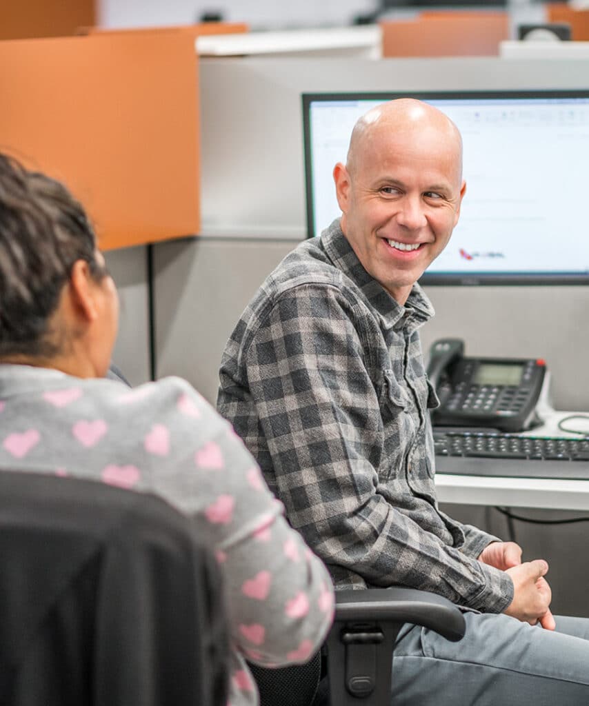 Two people talking in a cubicle